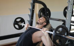 Man performing an incline bench press with a barbell, showing head and neck position to reduce neck pain from bench press.