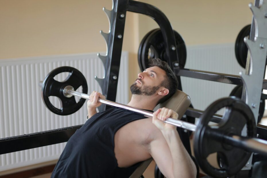 Man performing an incline bench press with a barbell, showing head and neck position to reduce neck pain from bench press.