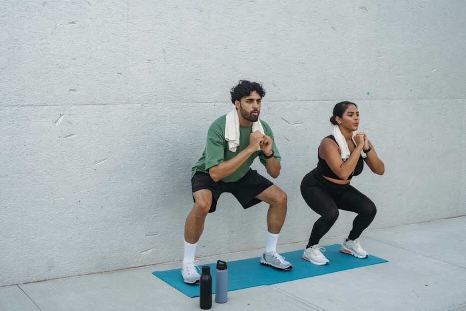 Two people doing bodyweight squats on a mat outdoors, a simple exercise option when thighs hurt after squats.