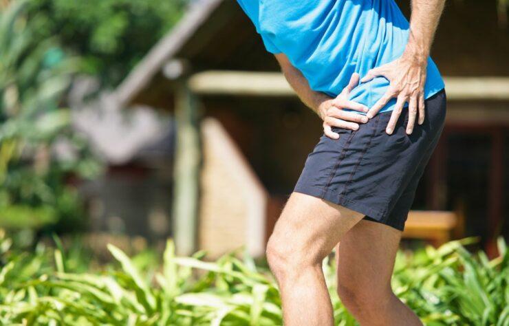 Pain hip when walking causing discomfort in active adult holding hip outdoors